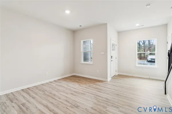 an empty room with wooden floor and windows