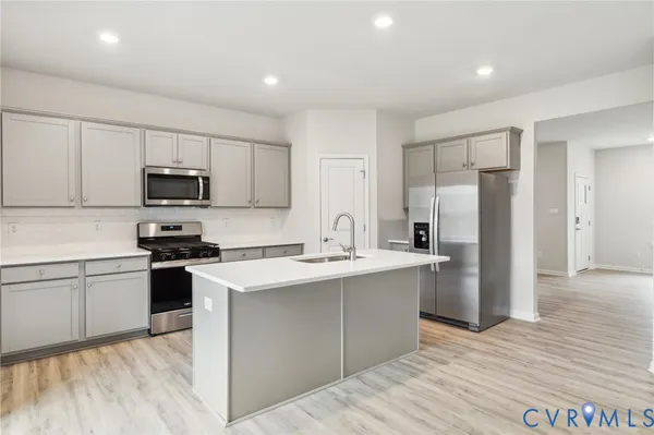 a kitchen with stainless steel appliances granite countertop a stove top oven a sink and a refrigerator