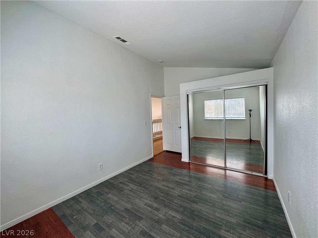 73 Sea Holly Way Henderson, NV 89074 - Photo 53 of 59 Unfurnished bedroom with vaulted ceiling, a closet, dark wood-type flooring, and a textured wall