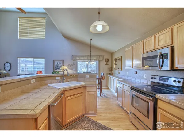 a kitchen with stainless steel appliances granite countertop a sink a stove counter space and cabinets
