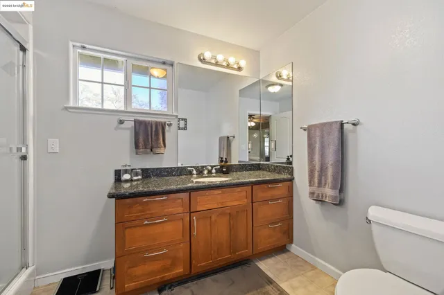 a bathroom with a granite countertop sink a toilet a large mirror and shower