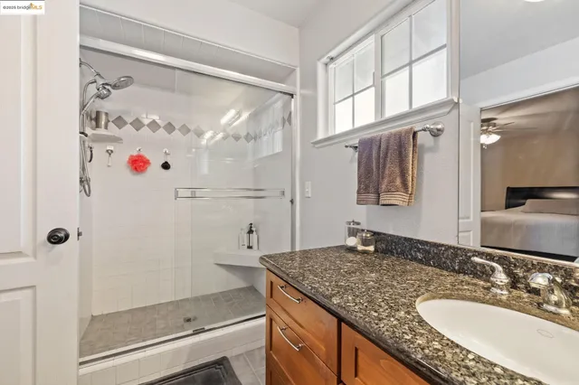 a bathroom with a granite countertop shower sink and mirror