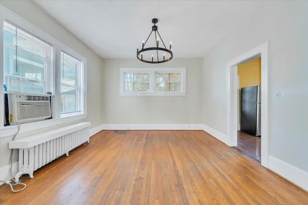 a view of an empty room with wooden floor and window