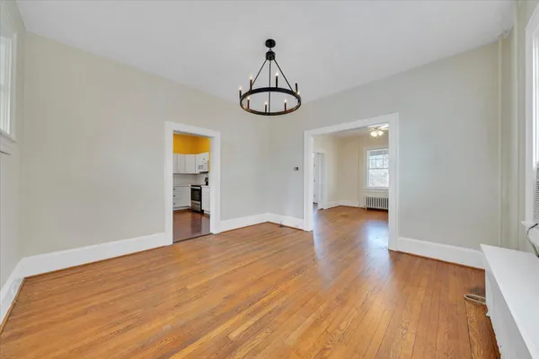 a view of an empty room with wooden floor and window