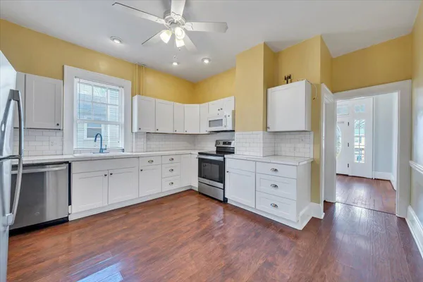 a large kitchen with cabinets wooden floor and stainless steel appliances