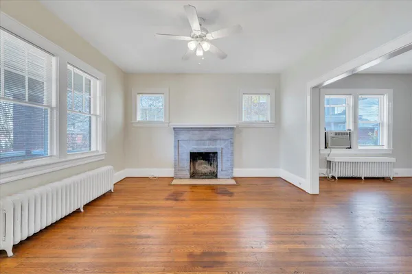 a view of a livingroom with a fireplace wooden floor and windows
