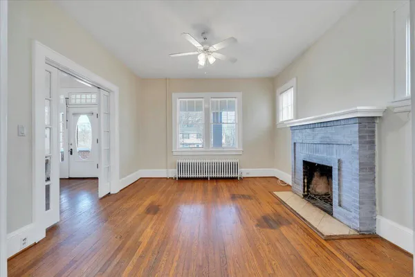 a view of an empty room with wooden floor fireplace and a window