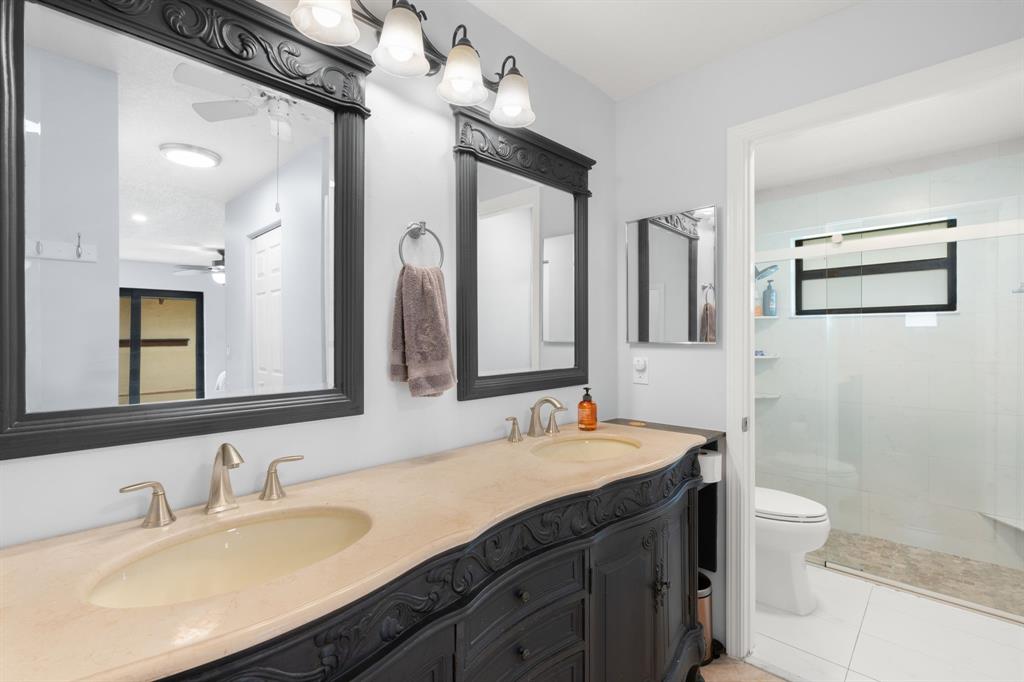 9106 Southwest 22nd Street, Unit D Boca Raton, FL 33428 - Photo 18 of 41 a bathroom with a double vanity sink toilet and a mirror