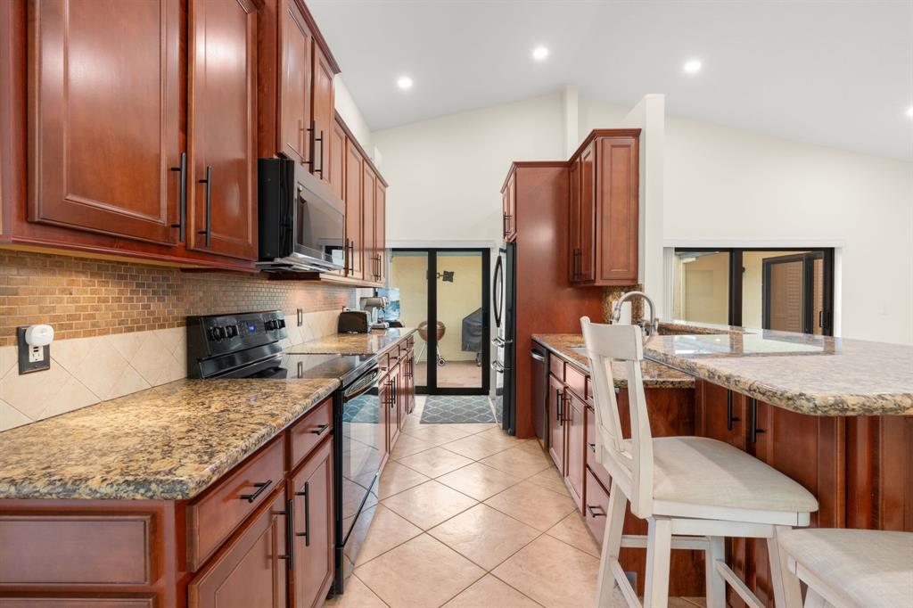 9106 Southwest 22nd Street, Unit D Boca Raton, FL 33428 - Photo 4 of 41 a kitchen with stainless steel appliances granite countertop wooden cabinets a stove top oven a sink and dishwasher