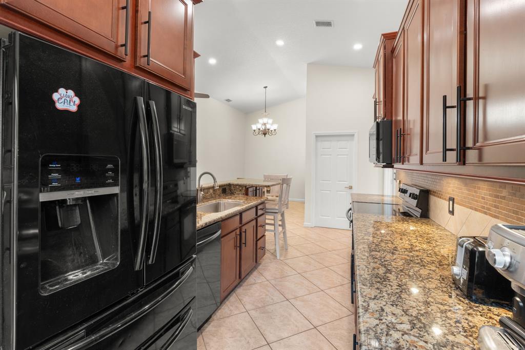 9106 Southwest 22nd Street, Unit D Boca Raton, FL 33428 - Photo 6 of 41 a large kitchen with granite countertop a refrigerator and a stove