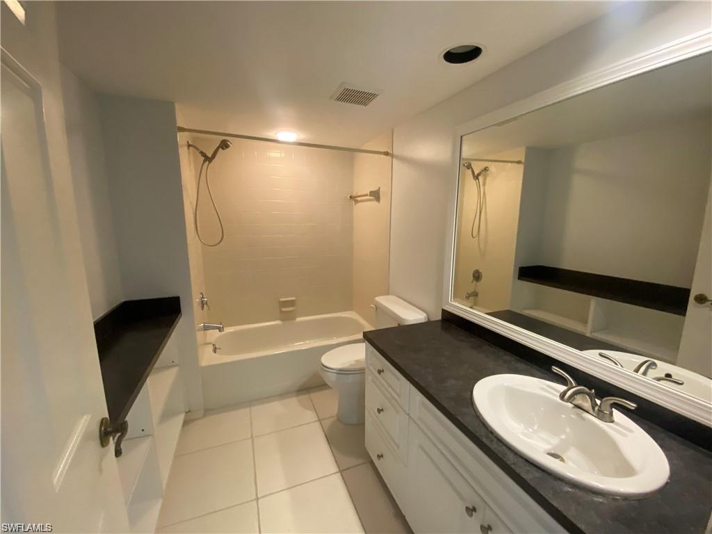 705 Augusta Boulevard, Unit 7055 Naples, FL 34113 - Photo 10 of 18 a bathroom with a granite countertop sink toilet and shower
