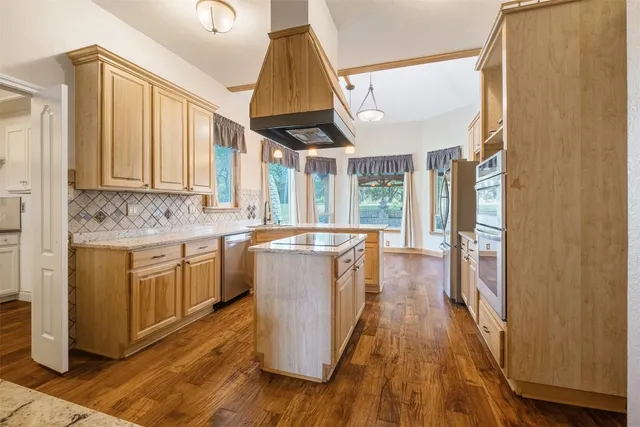 a kitchen with kitchen island granite countertop white cabinets and wooden floor