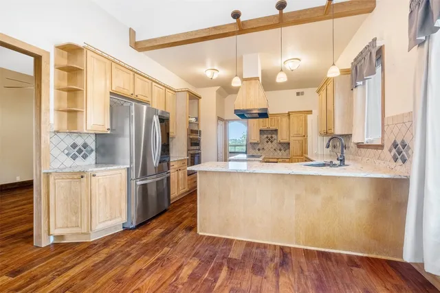 a kitchen with stainless steel appliances granite countertop a refrigerator a sink and a stove