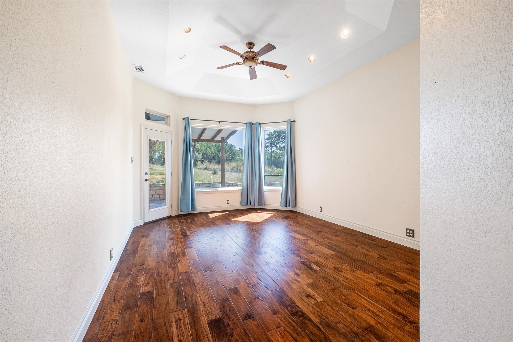 360 Sunset Ridge Drive Liberty Hill, TX 78642 - Photo 19 of 40 an empty room with wooden floor chandelier fan and windows