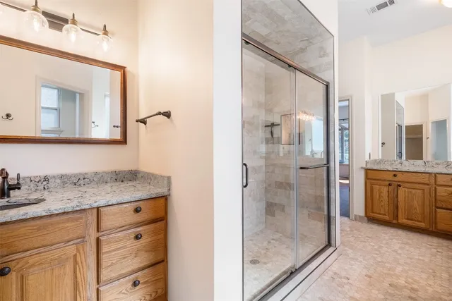 a bathroom with a granite countertop sink mirror and a shower