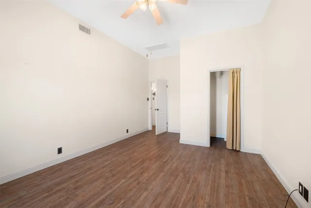an empty room with wooden floor and ceiling fan