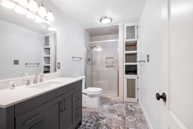 a bathroom with a sink a toilet a shower and a mirror