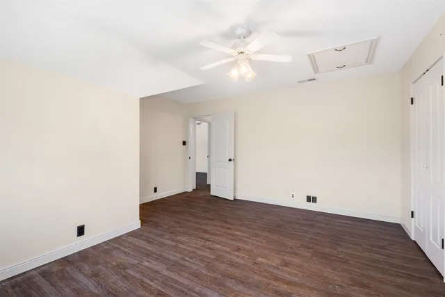 an empty room with wooden floor and fan