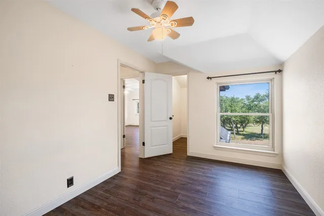 a view of an empty room with window wooden floor and a chandelier fan