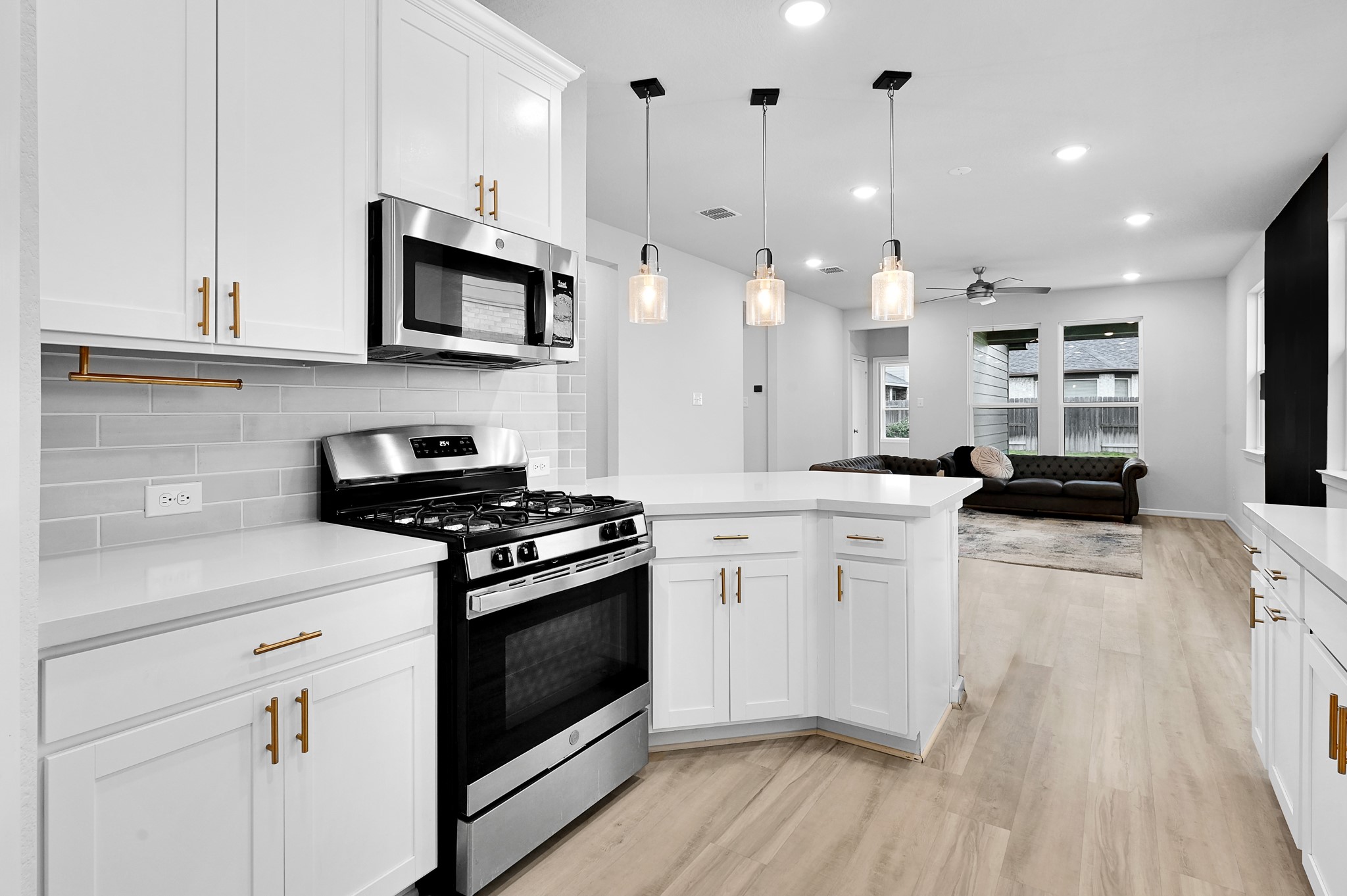 9119 Brixham Drive Cypress, TX 77433 - Photo 9 of 23 a kitchen with stainless steel appliances white cabinets a sink a stove a microwave and wooden floors