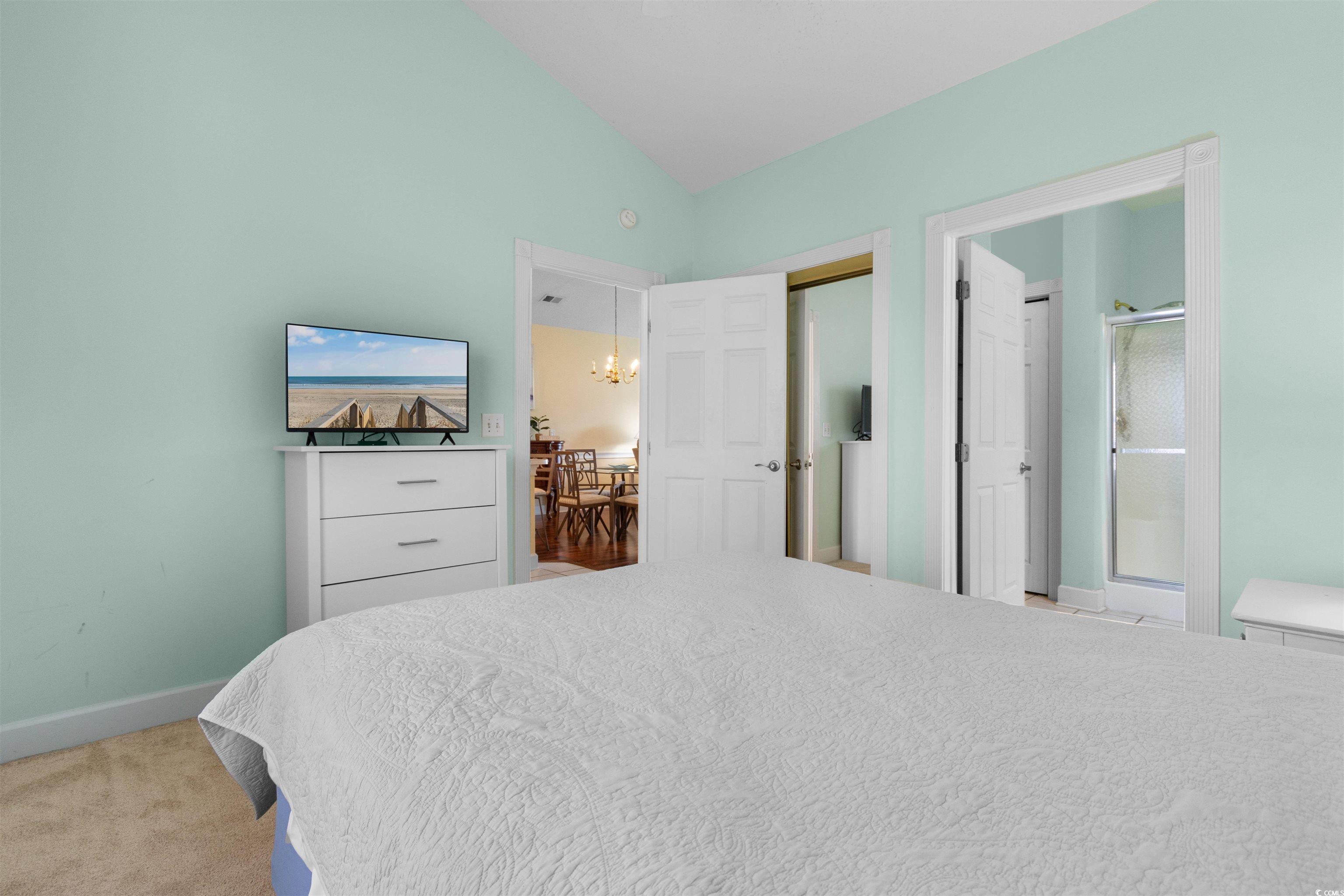 4856 Carnation Circle, Unit 302 Myrtle Beach, SC 29577 - Photo 9 of 28 Bedroom featuring carpet floors, a chandelier, lofted ceiling, and ensuite bath