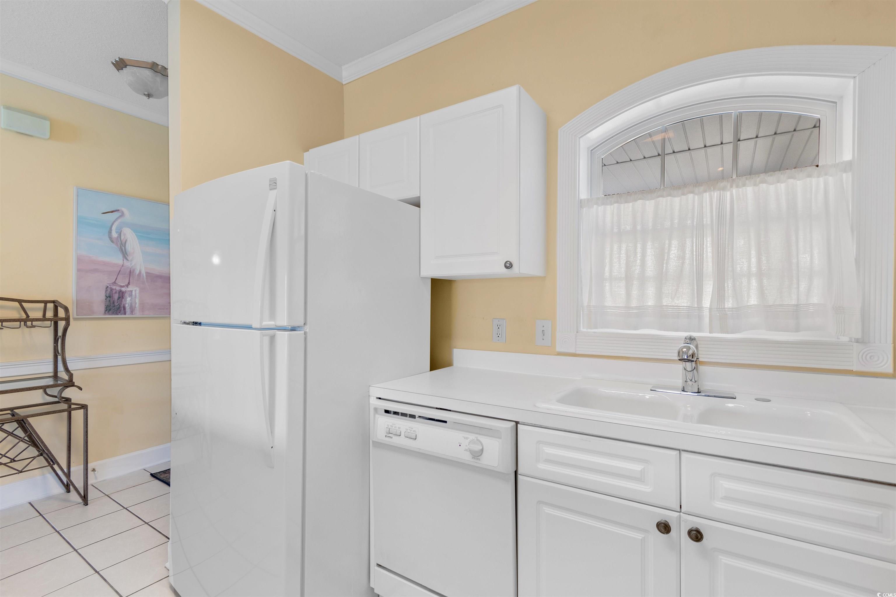 4856 Carnation Circle, Unit 302 Myrtle Beach, SC 29577 - Photo 16 of 28 Kitchen with light countertops, white cabinetry, white appliances, light tile patterned flooring, and ornamental molding