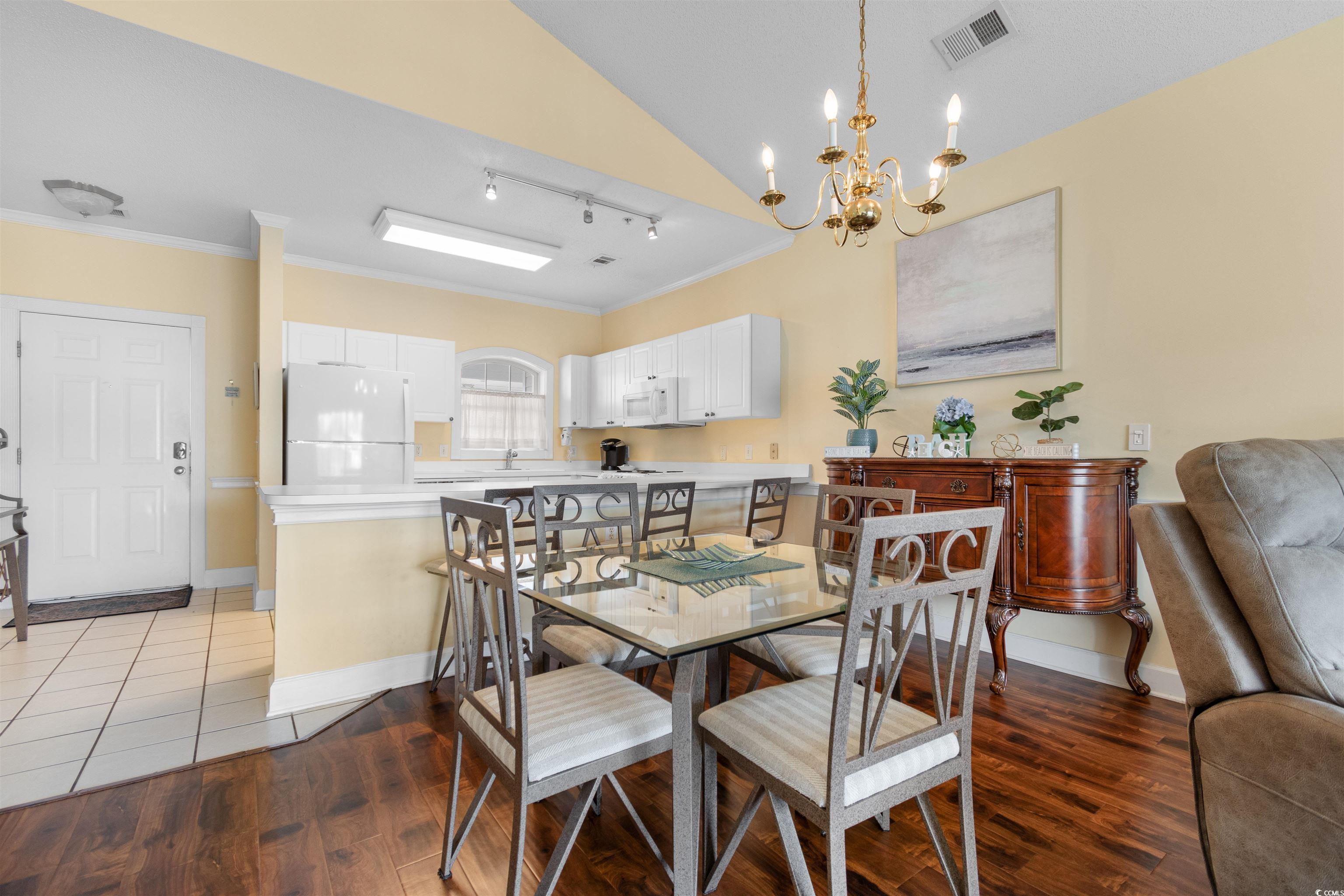 4856 Carnation Circle, Unit 302 Myrtle Beach, SC 29577 - Photo 18 of 28 Dining area with rail lighting, vaulted ceiling, dark wood-style flooring, crown molding, and a chandelier
