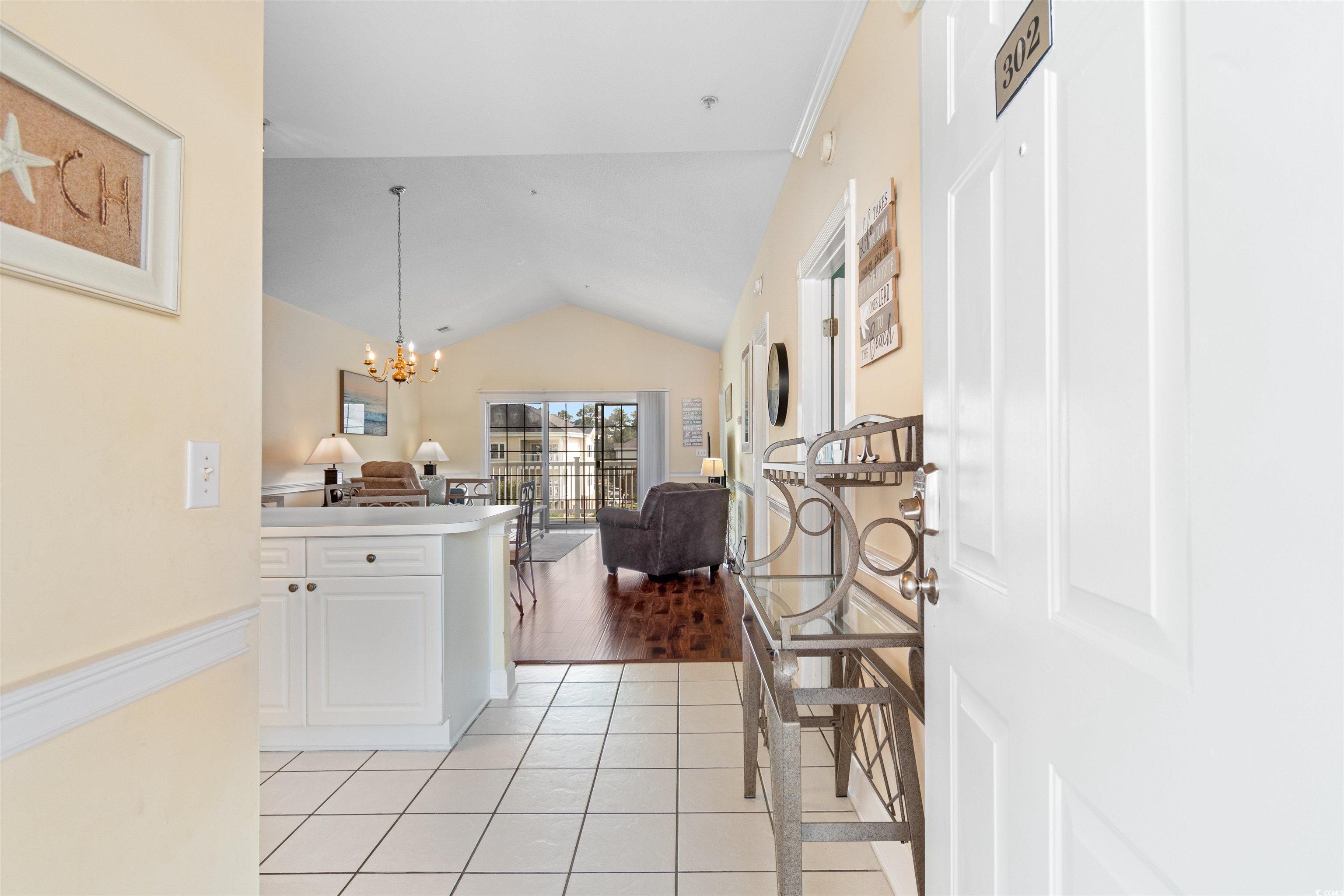 4856 Carnation Circle, Unit 302 Myrtle Beach, SC 29577 - Photo 26 of 28 Kitchen with vaulted ceiling, light tile patterned flooring, open floor plan, a chandelier, and white cabinetry