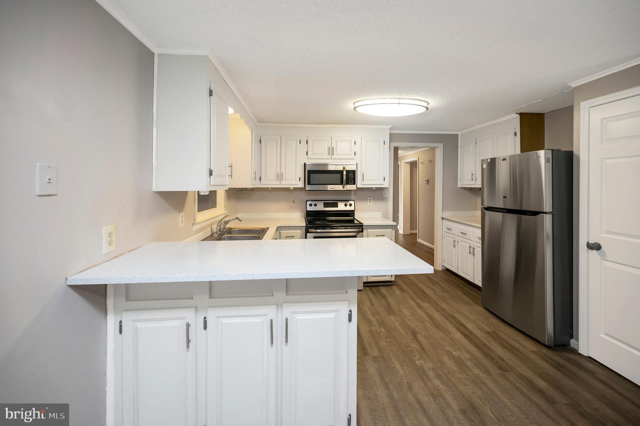12402 Toll House Road Spotsylvania, VA 22551 - Photo 18 of 59 a kitchen with a refrigerator a stove a sink and white cabinets with wooden floor