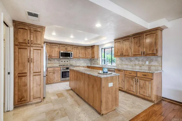 a kitchen with stainless steel appliances granite countertop a refrigerator and a stove top oven