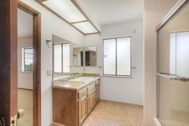 a bathroom with a granite countertop bathtub shower sink and toilet