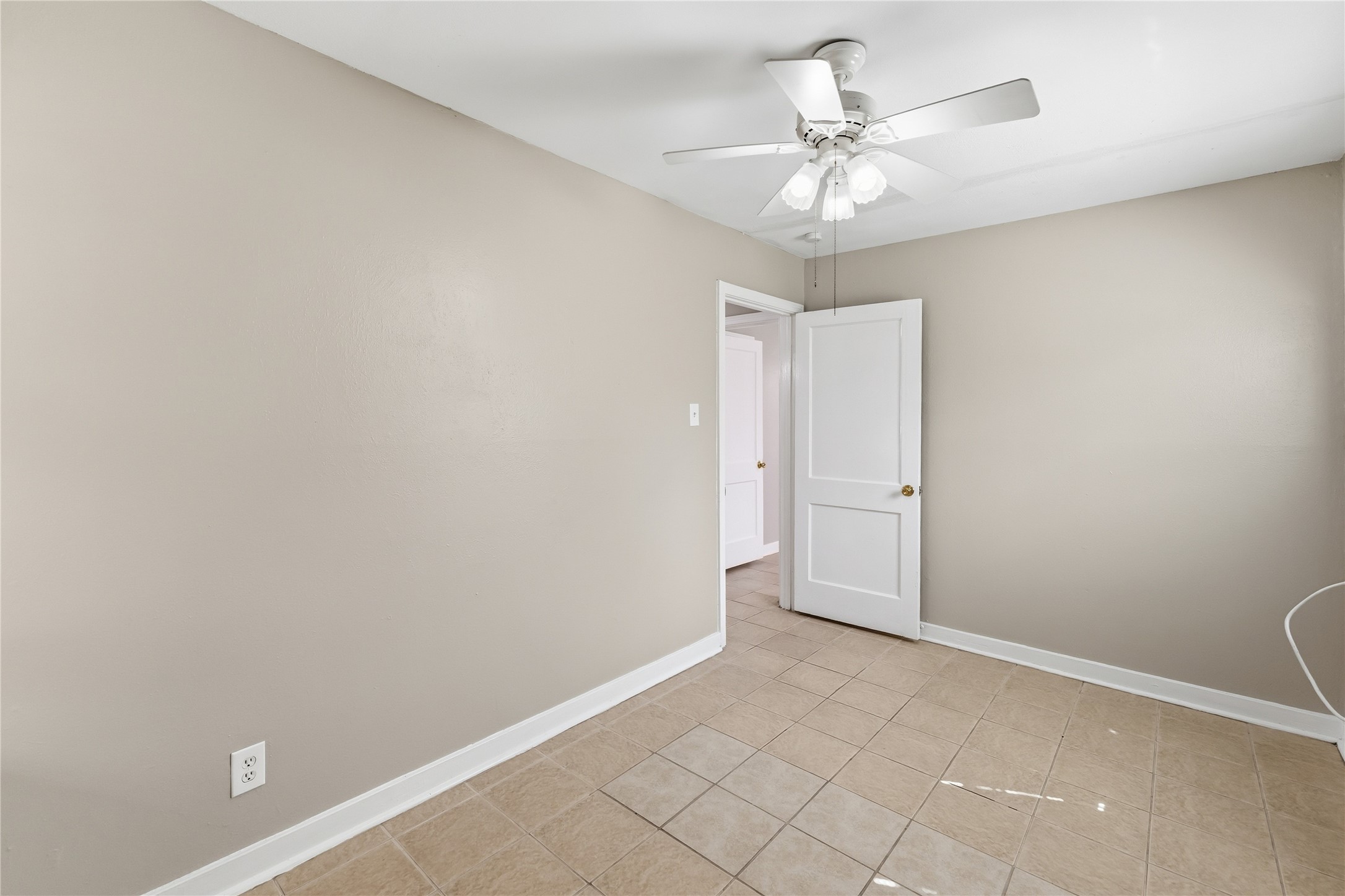 4814 Burma Road Houston, TX 77033 - Photo 13 of 16 This room features neutral walls, tile flooring, and ample natural light from two windows with blinds. It includes a ceiling fan, wall-mounted air conditioning, and a small closet with an open door.