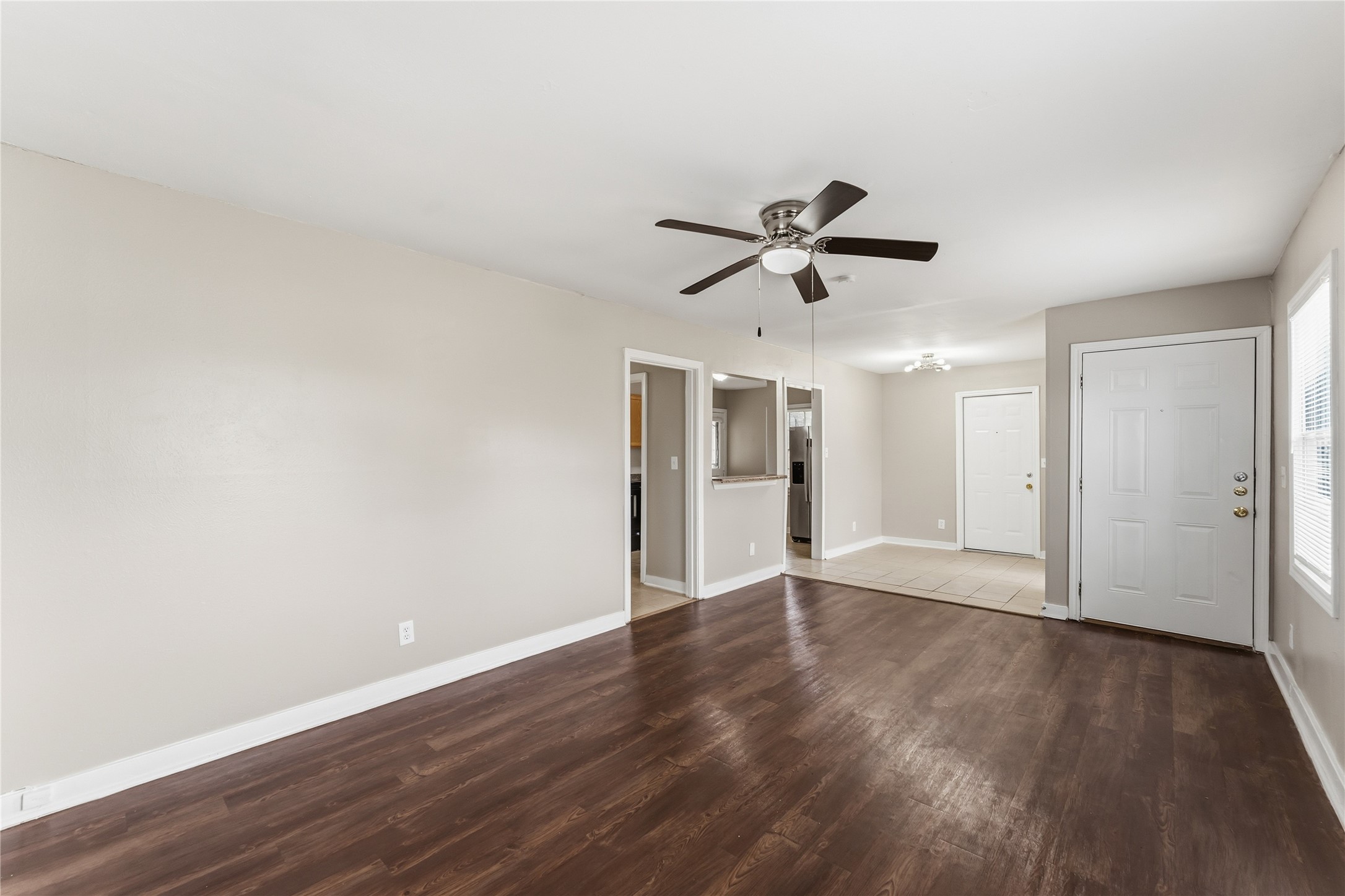 4814 Burma Road Houston, TX 77033 - Photo 3 of 16 Spacious, open-concept living area with neutral walls, and a ceiling fan. The room connects to an entryway with tile flooring, offering a bright and welcoming atmosphere.