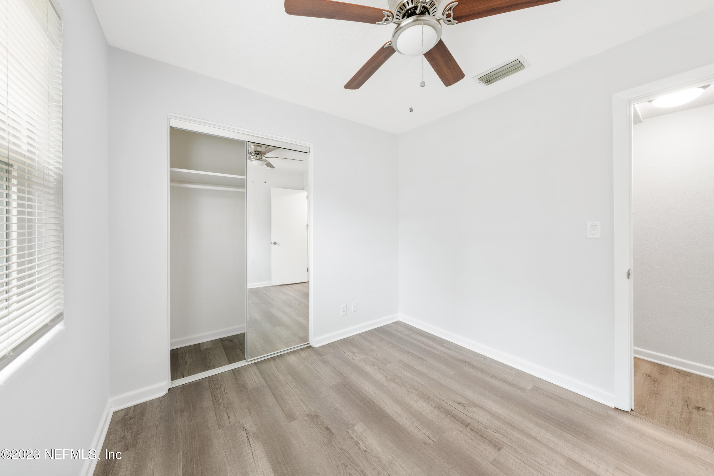 2704 Devonwood Road Jacksonville, FL 32211 - Photo 17 of 31 an empty room with wooden floor fan and windows