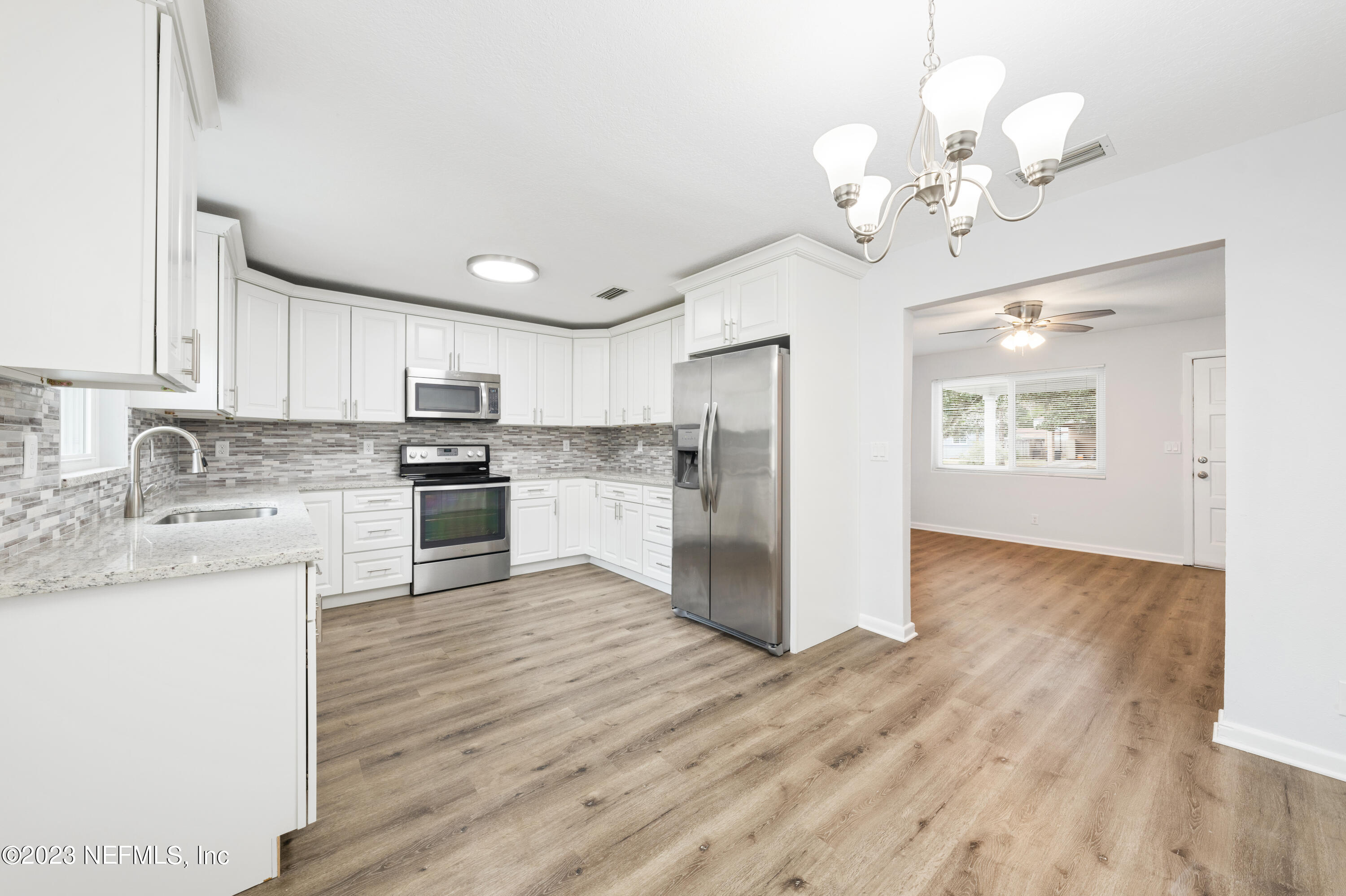 2704 Devonwood Road Jacksonville, FL 32211 - Photo 9 of 31 a kitchen with stainless steel appliances granite countertop a refrigerator a sink dishwasher a dining table and chairs with wooden floor