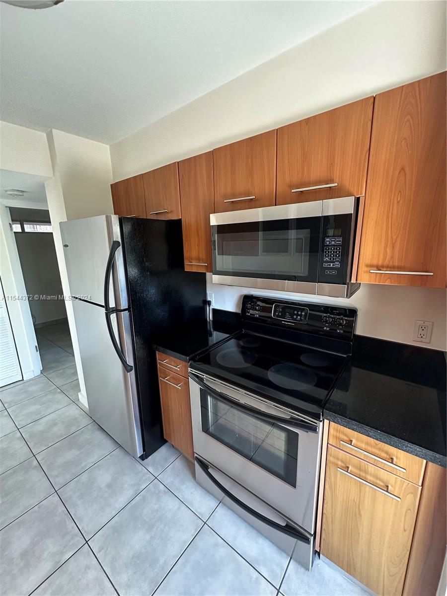 Nirvana Condominiums Miami, FL 33138 - Photo 12 of 13 a kitchen with granite countertop a refrigerator and a stove top oven