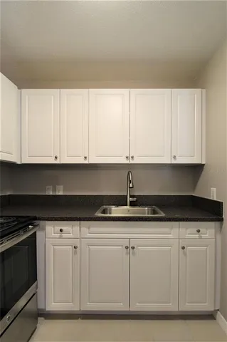 a kitchen with granite countertop white cabinets and stainless steel appliances