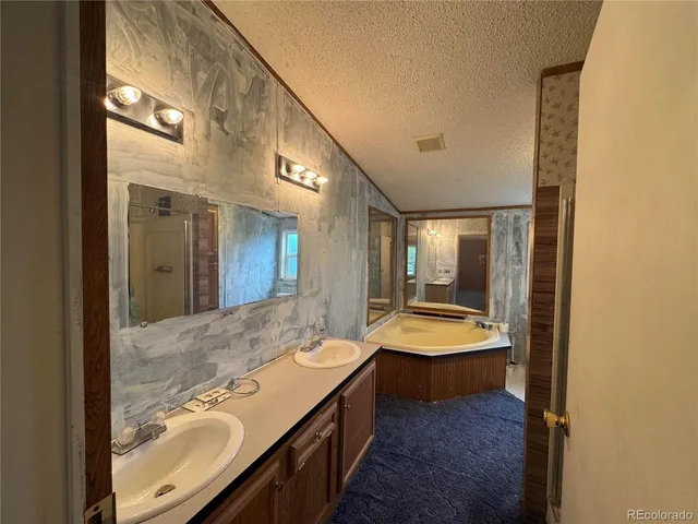 a bathroom with a granite countertop double vanity sink and mirror with bathtub
