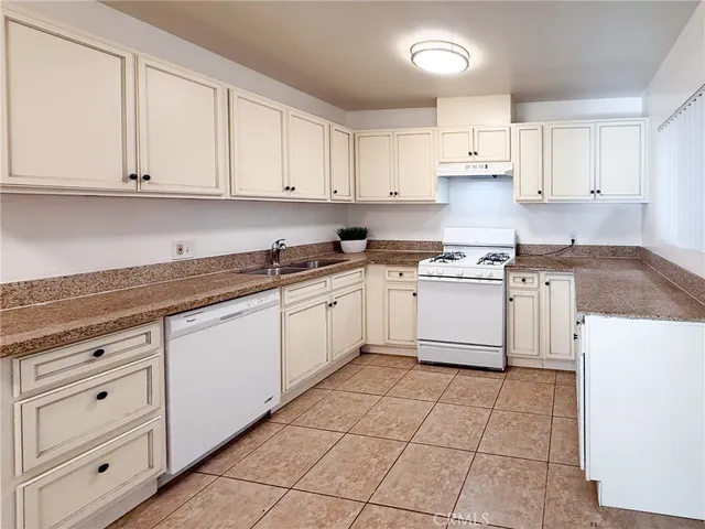 a white kitchen with granite countertop white cabinets stainless steel appliances with a sink and dishwasher