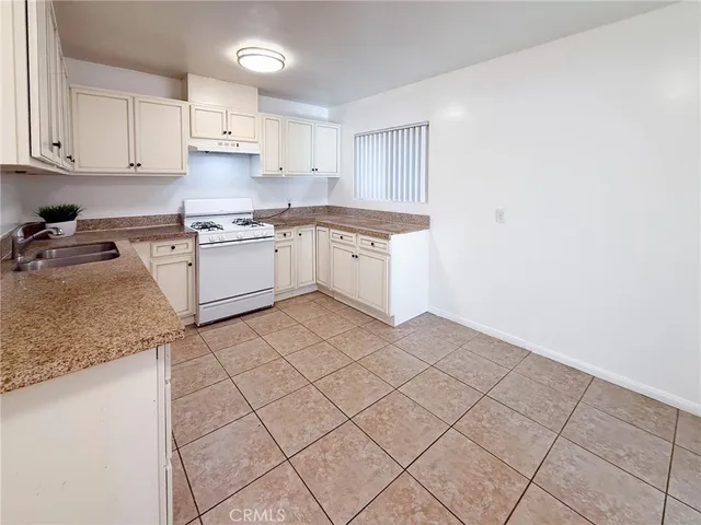 a kitchen with granite countertop white cabinets and white appliances