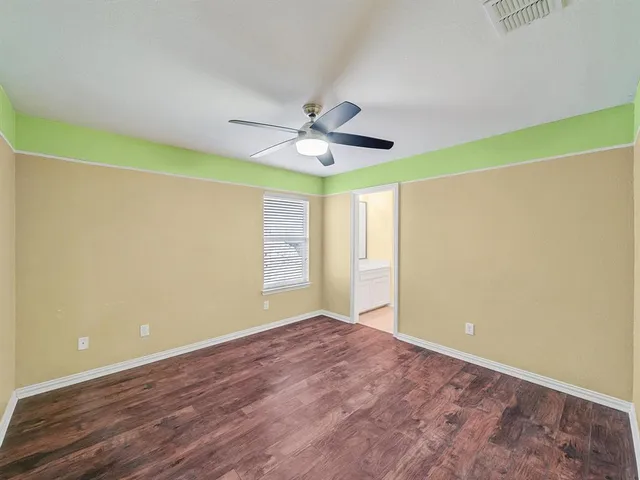 an empty room with windows and ceiling fan