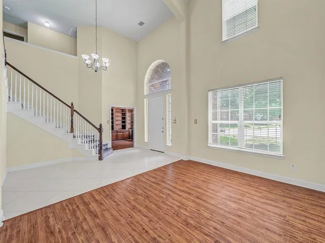 an empty room with wooden floor fan and windows