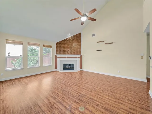 an empty room with wooden floor fireplace and windows