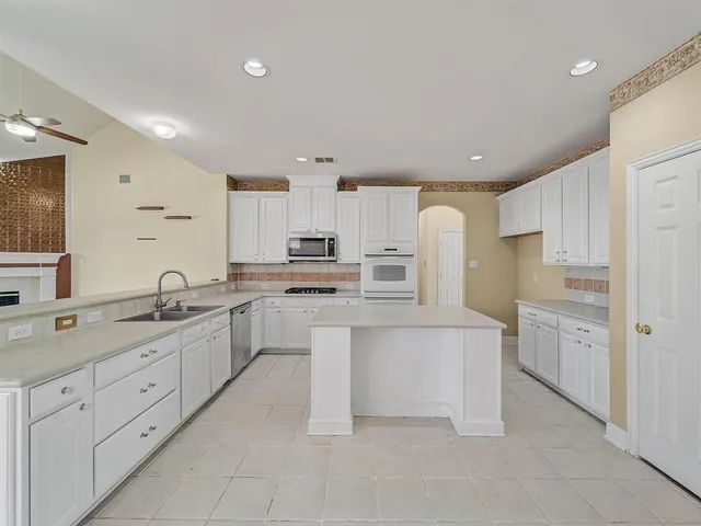 a large white kitchen with stainless steel appliances cabinets and a sink