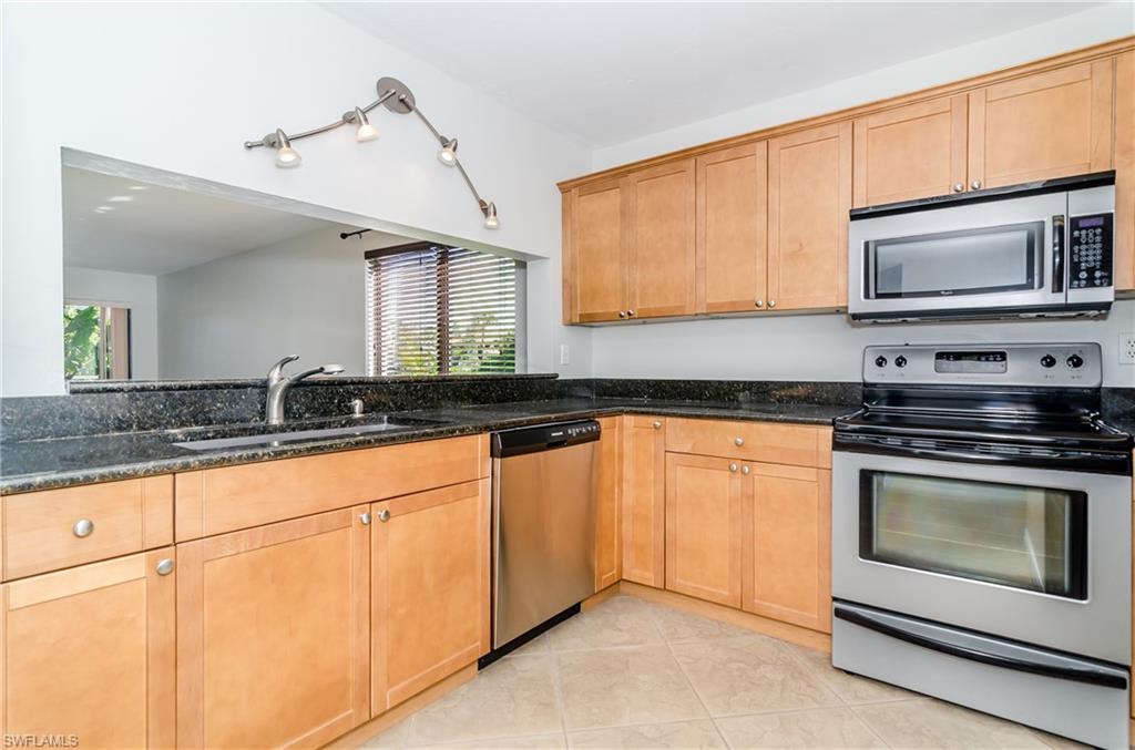 1220 Commonwealth Circle, Unit M106 Naples, FL 34116 - Photo 3 of 16 a kitchen with stainless steel appliances granite countertop a stove a sink and a microwave