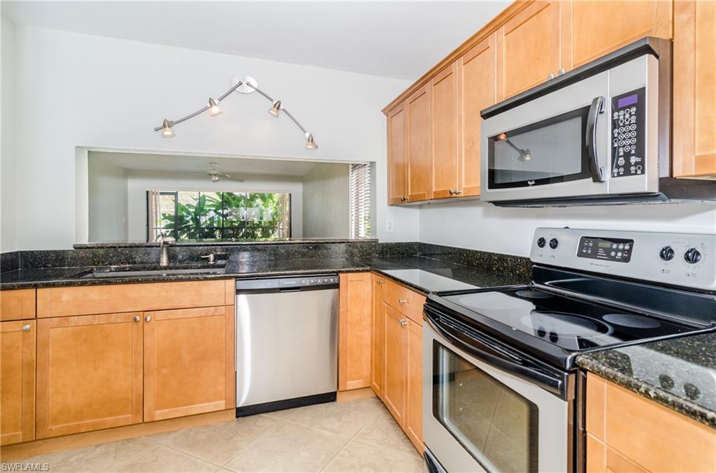 1220 Commonwealth Circle, Unit M106 Naples, FL 34116 - Photo 8 of 16 a kitchen with stainless steel appliances granite countertop a stove a sink and a microwave