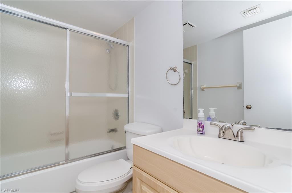 1220 Commonwealth Circle, Unit M106 Naples, FL 34116 - Photo 9 of 16 a bathroom with a sink toilet vanity and shower