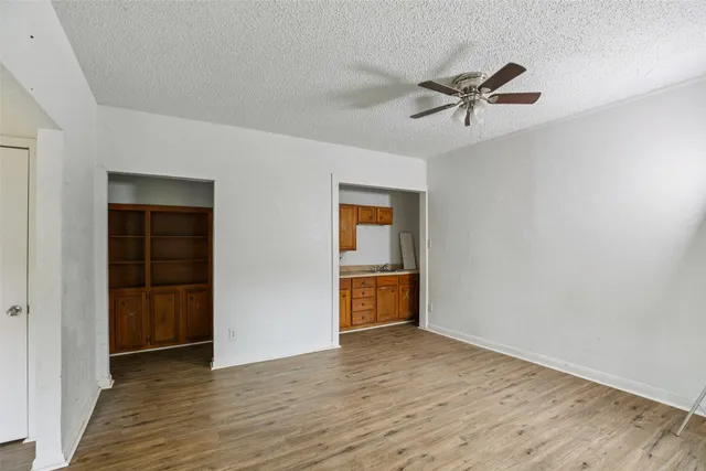a view of empty room with wooden floor and ceiling fan
