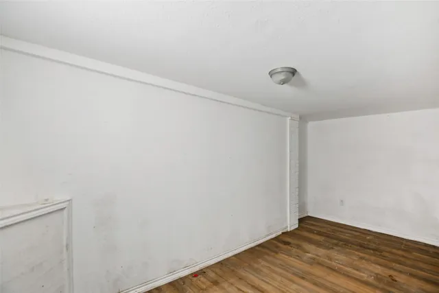 a view of an empty room with wooden floor and closet