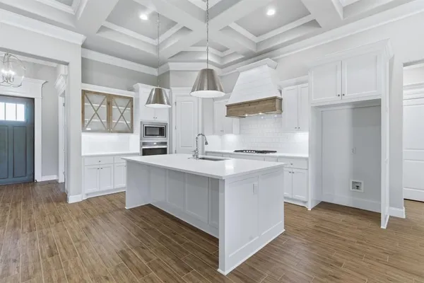 a kitchen with stainless steel appliances granite countertop a refrigerator a sink dishwasher and white cabinets with wooden floor